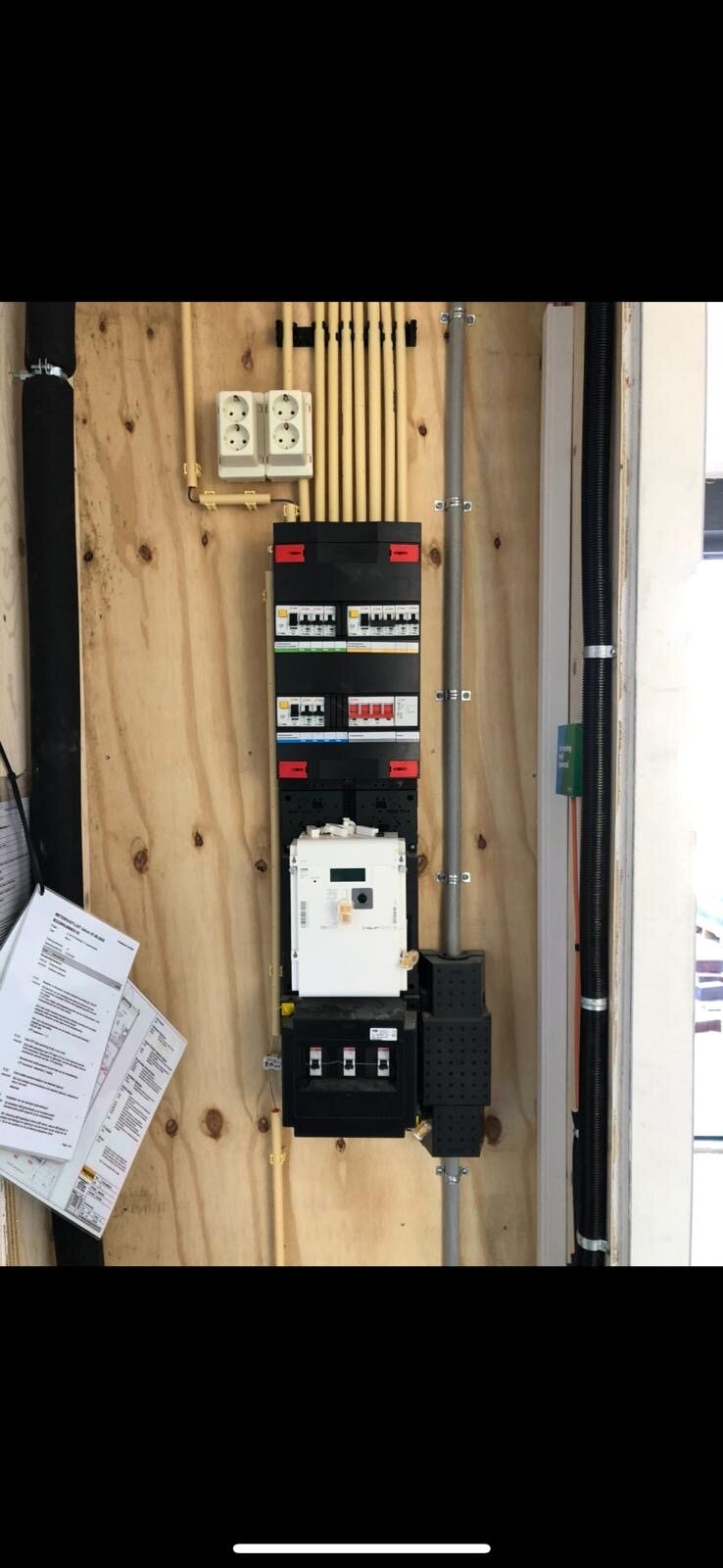 Elektrische aansluiting en meter op een houten paneel